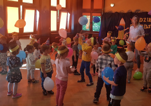 Zabawa z balonikami przy muzyce – dzieci tańczą przy muzyce, starając się podbijać baloniki w górę tak, by utrzymać je w powietrzu.